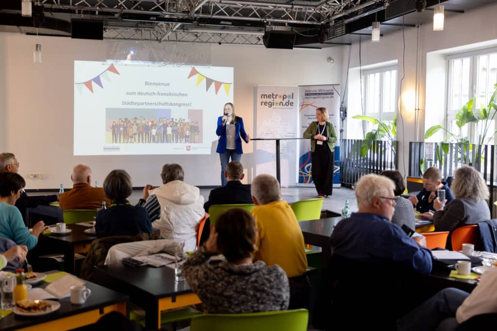 Vera Glaser (auf der Bühne links) und Laure Dréano-Mayer (auf der Bühne rechts) von der Antenne Métropole hießen das Publikum herzlich zum abschließenden Städtepartnerschaftskongress willkommen (Foto: Lam Nguyễn Tiến)